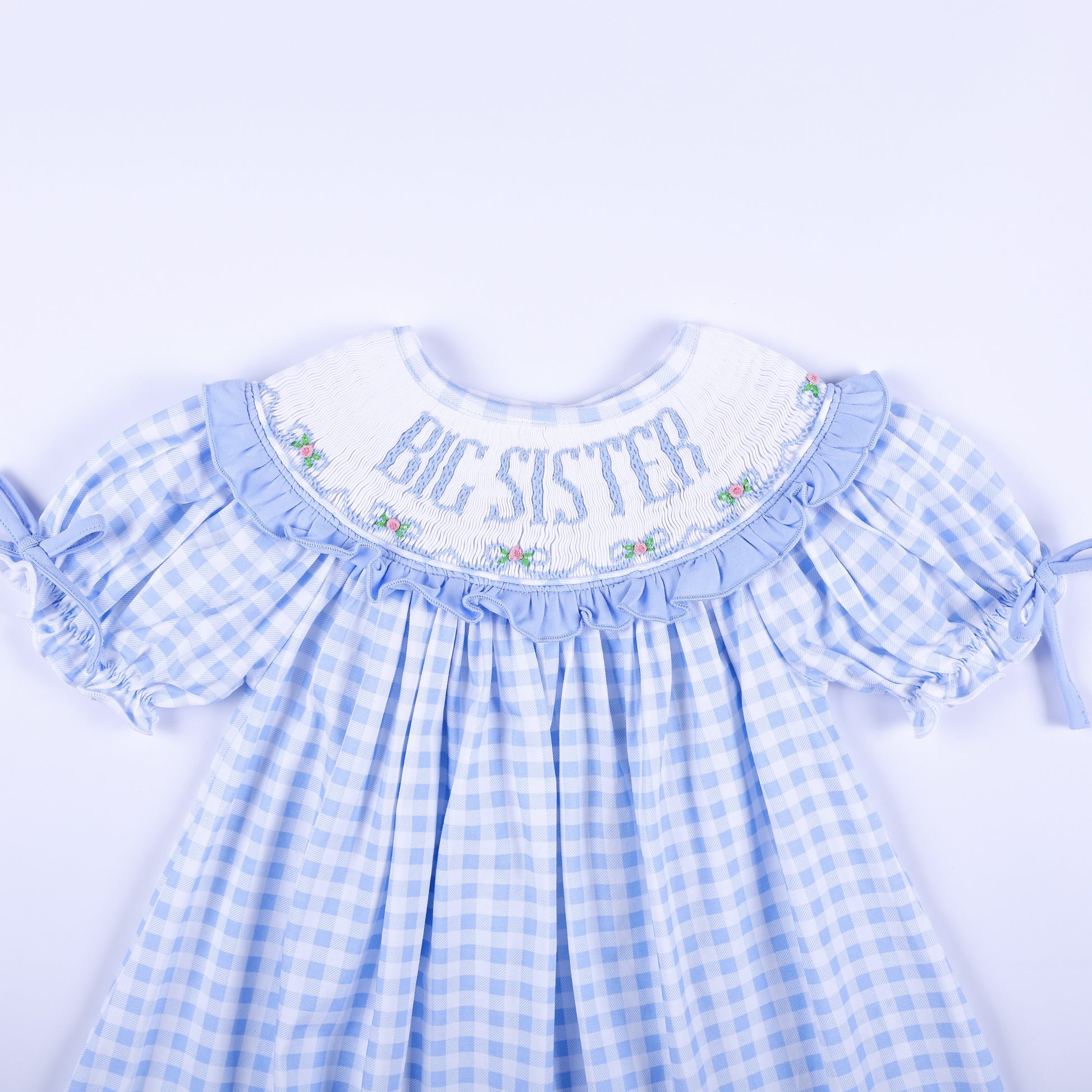 Close-up view of the hand-smocked neckline with Big Sister embroidery on a light blue gingham dress.