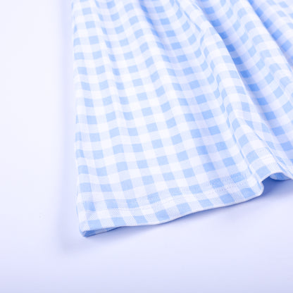 Close-up view of the light blue and white gingham woven fabric hem on a boutique hand-smocked girls dress.