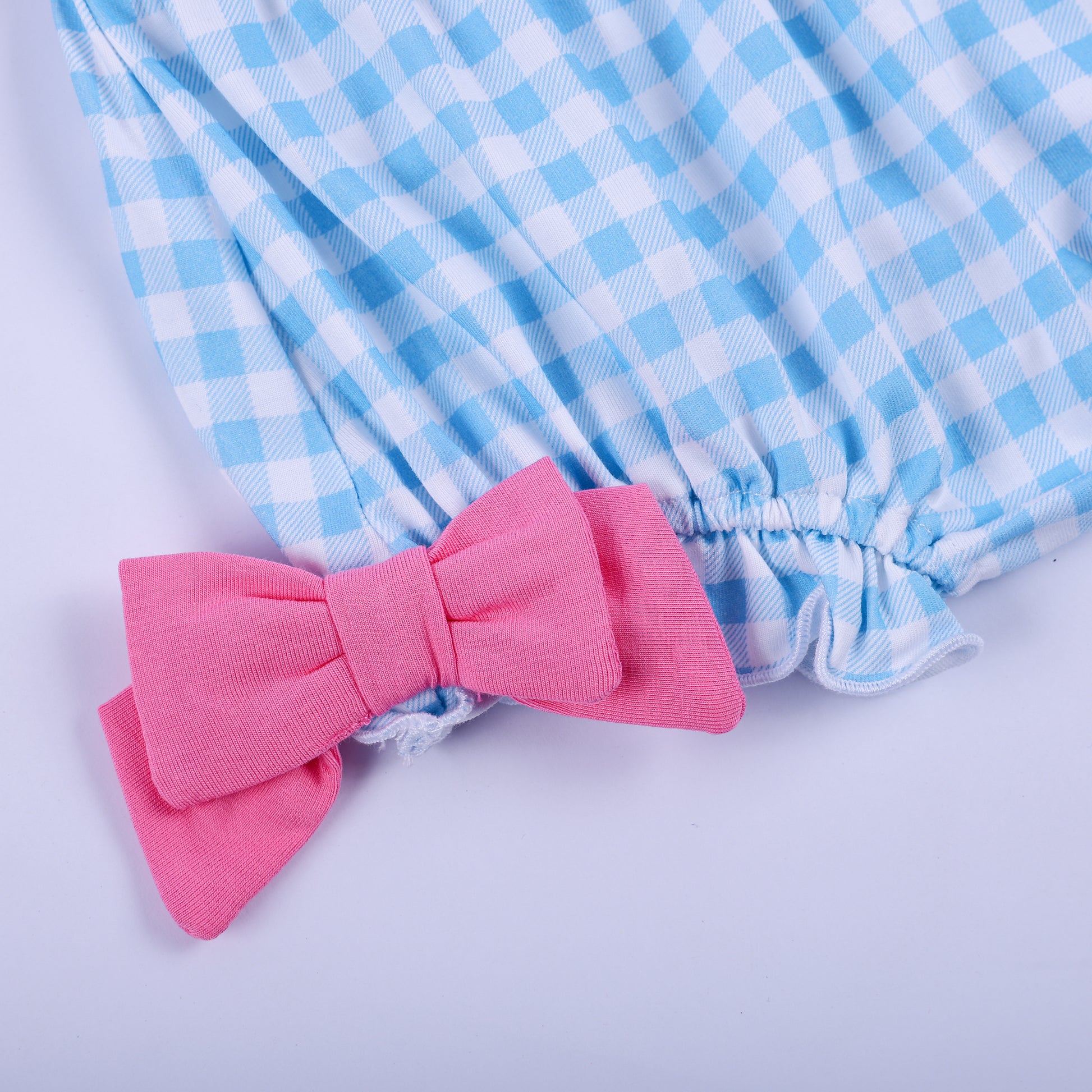 Detail of blue gingham diaper cover bloomer featuring soft elastic leg opening and pink side bow accent.