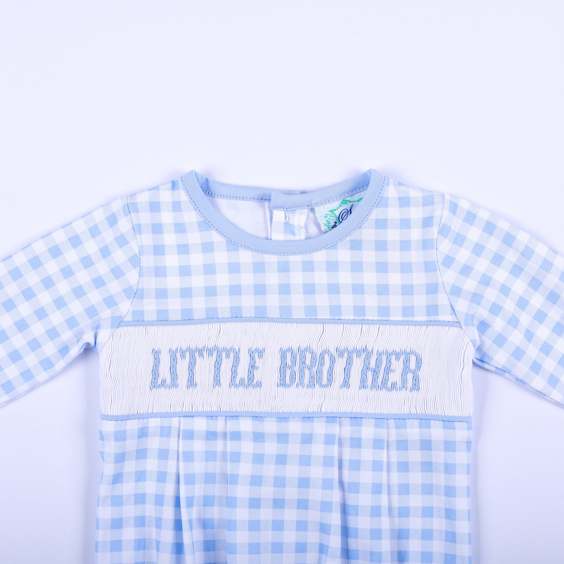 Close up of hand smocked chest bodice on blue gingham baby boy sleep sack layette with Little Brother text.