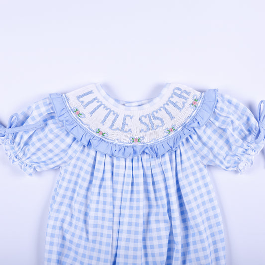Detailed front collar of blue gingham bubble showing hand-smocked Little Sister text and delicate rose embroidery.