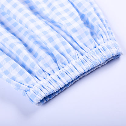 Close up view of elastic bottom hem on blue gingham hand smocked infant sleep sack layette gown for boys.