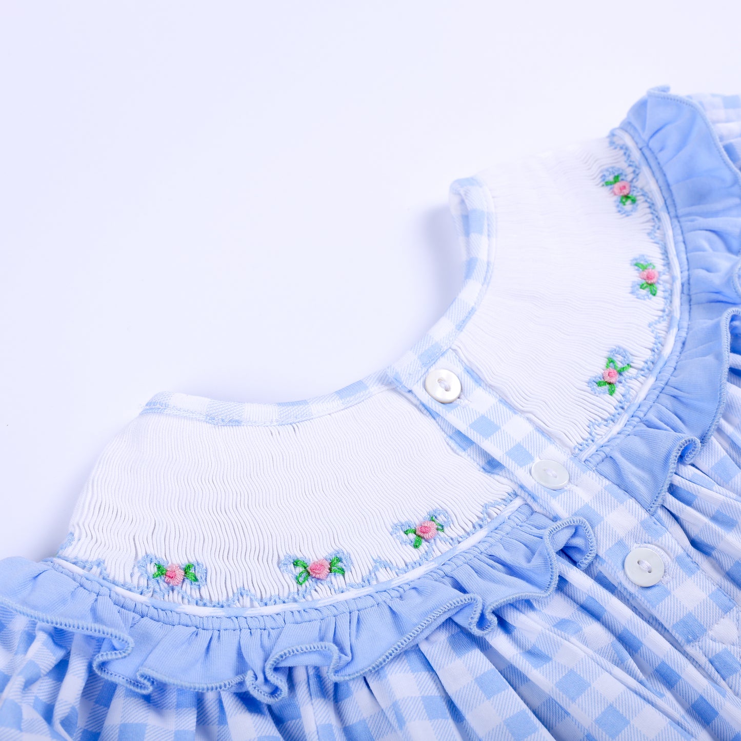 Close-up of back button closure and smocked collar detail on blue gingham Big Sister baby dress top.