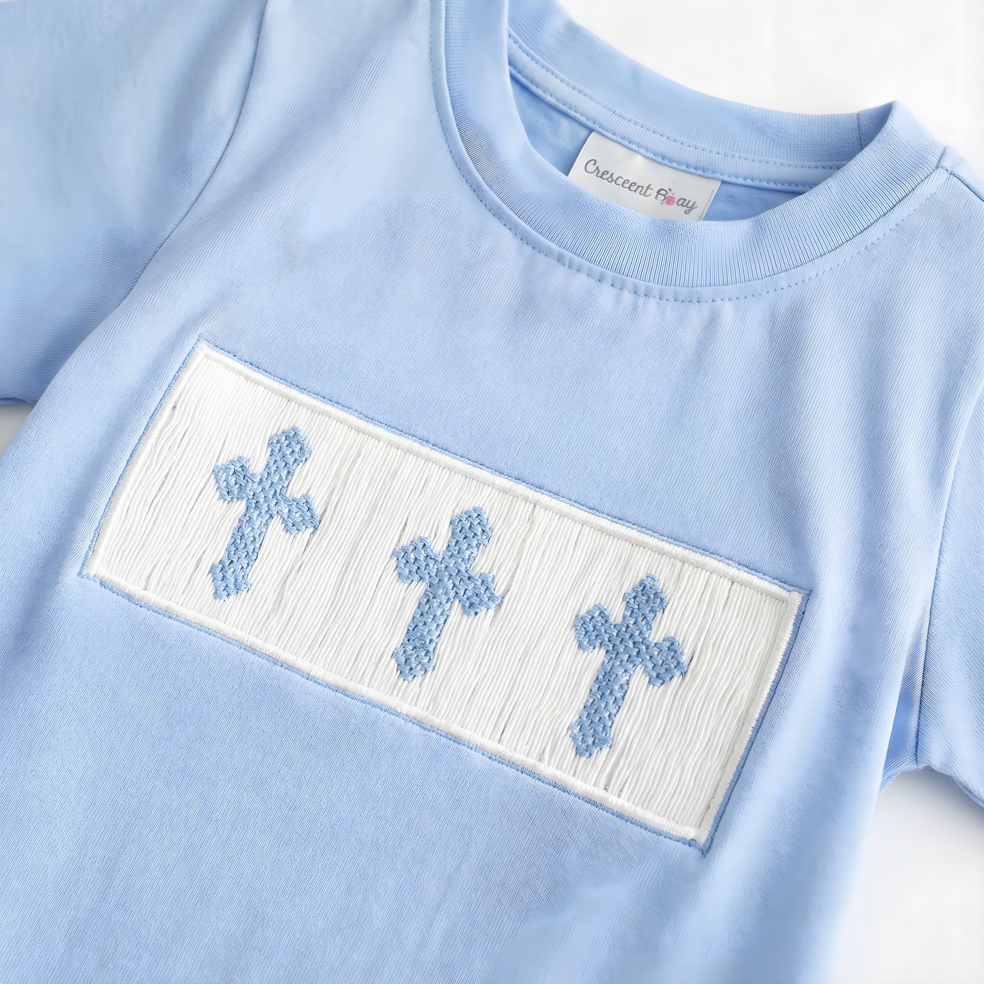 Blue boys shirt featuring a white hand-smocked panel with three blue embroidered crosses for Easter.