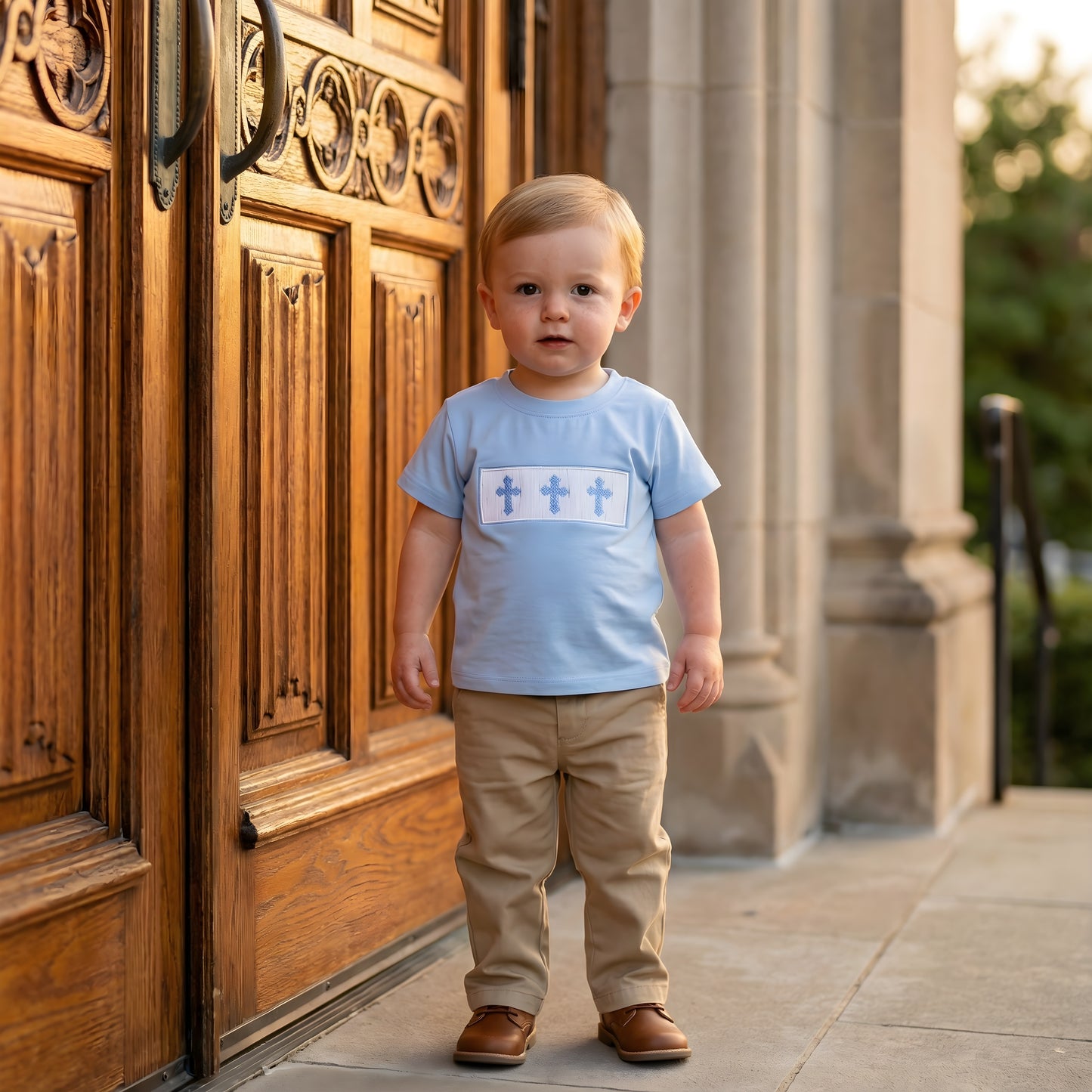 Toddler boy wearing blue hand smocked shirt with three blue crosses, perfect for Easter Sunday.