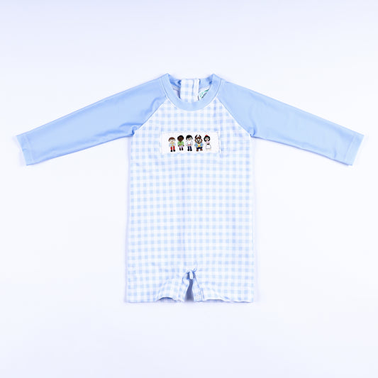Boys light blue gingham hand smocked handsome prince rash guard swimsuit featuring long sleeves and snap legs.