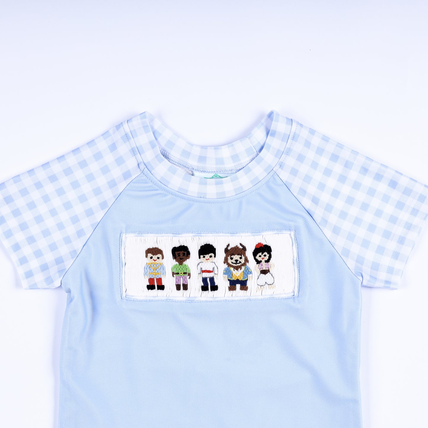 Boys light blue rash guard shirt featuring hand smocked prince embroidered chest plate and gingham short sleeves.