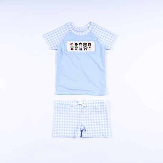 Boys handsome prince hand smocked two piece rash guard swimsuit with light blue top and gingham swim trunks front view.