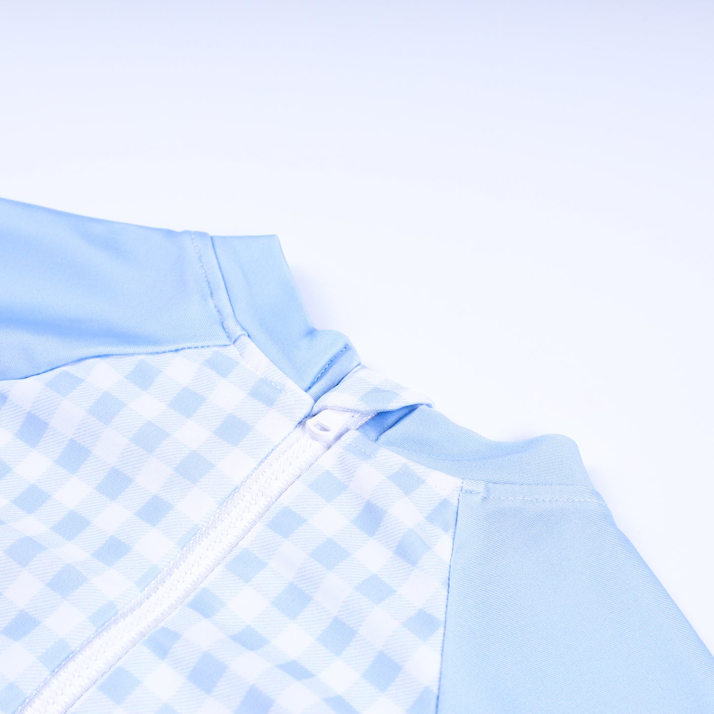 Close-up detail of back zipper closure on boys handsome prince hand smocked gingham one piece rash guard swimsuit.