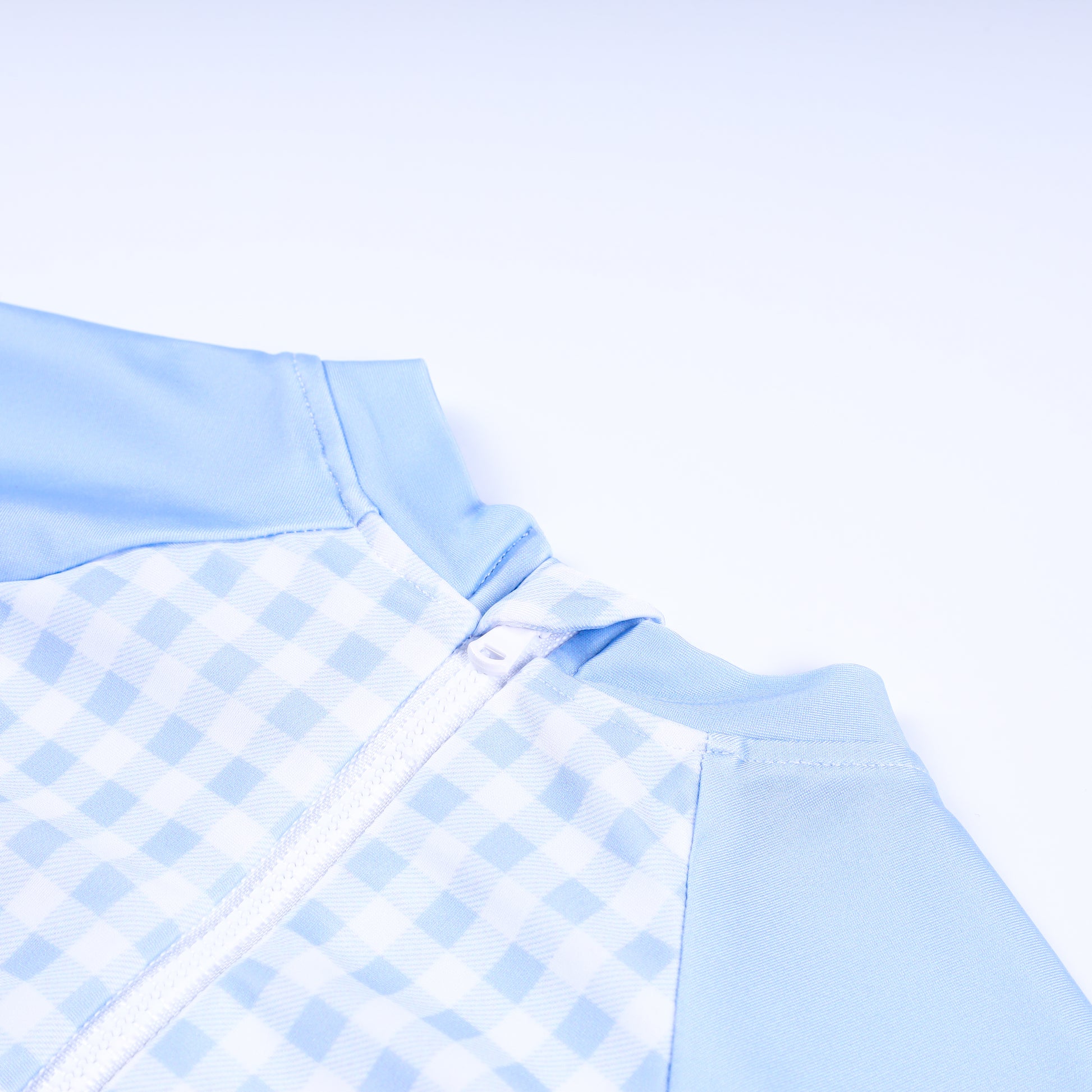 Close-up detail of back zipper closure on boys handsome prince hand smocked gingham one piece rash guard swimsuit.