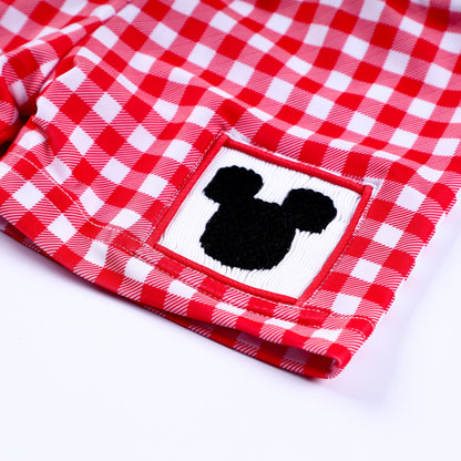 Detailed close-up of hand smocked black mouse silhouette patch on boys red and white gingham swim trunks.