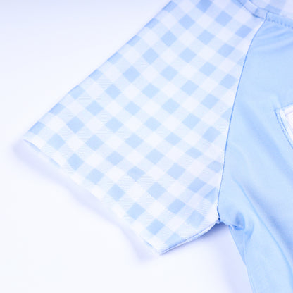 Detail view of light blue and white gingham check pattern sleeve on boys handsome prince hand smocked rash guard shirt.