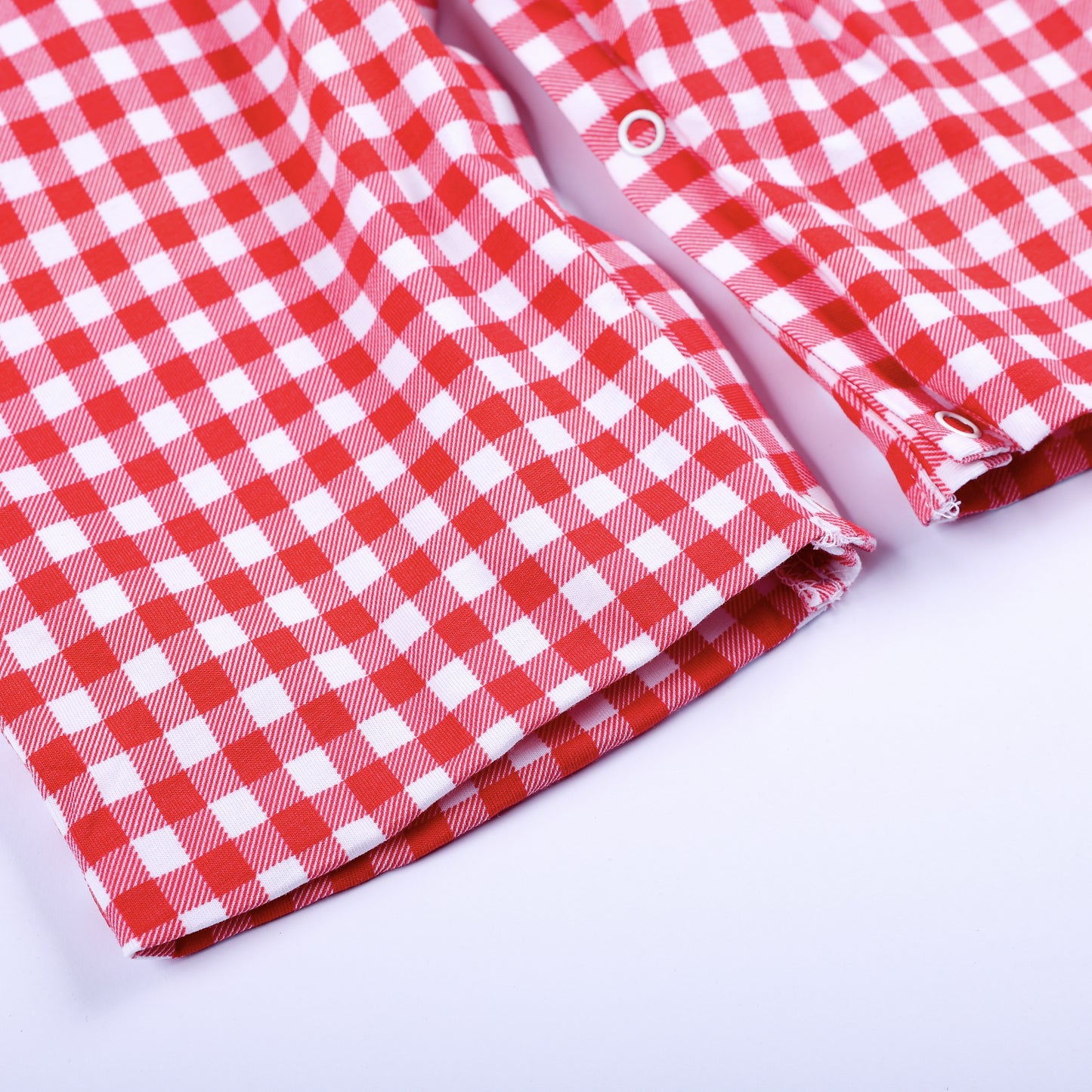 Detailed view of bottom leg opening and snap closures on classic red gingham hand smocked jon jon for baby boys.