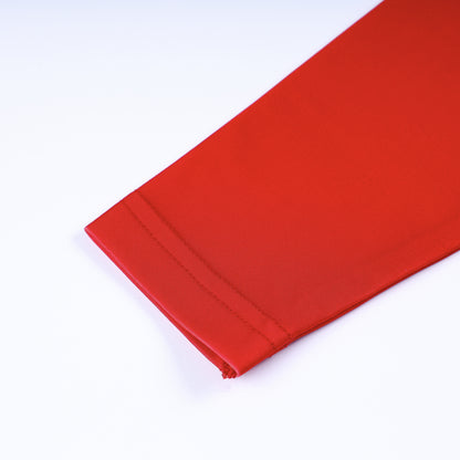 Close up shot showing fine hem stitching detail on the long sleeve cuff of the boys red swim rash guard.