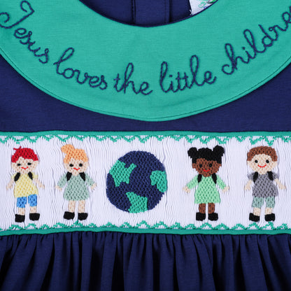 Centered close-up of the navy dress, highlighting the green embroidered collar script and smocked children around a globe.