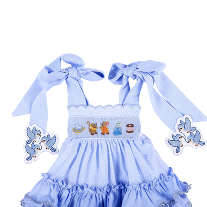 Front detail of Cinderella hand smocked blue ruffle top showing character chest embroidery and tied bow straps.