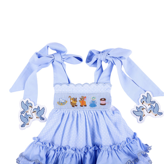Front detail of Cinderella hand smocked blue ruffle top showing character chest embroidery and tied bow straps.