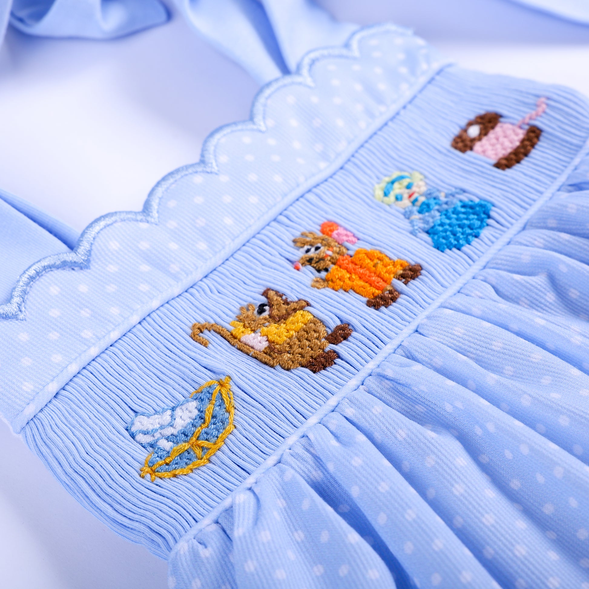 Detailed view of hand smocked chest panel with hand embroidered Cinderella mice, glass slipper, and thread spool.