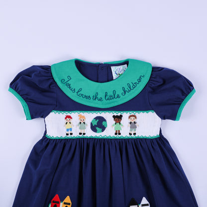 Detailed close-up of the hand-smocked bodice on the navy dress, featuring diverse children and a globe, and the collar embroidery.