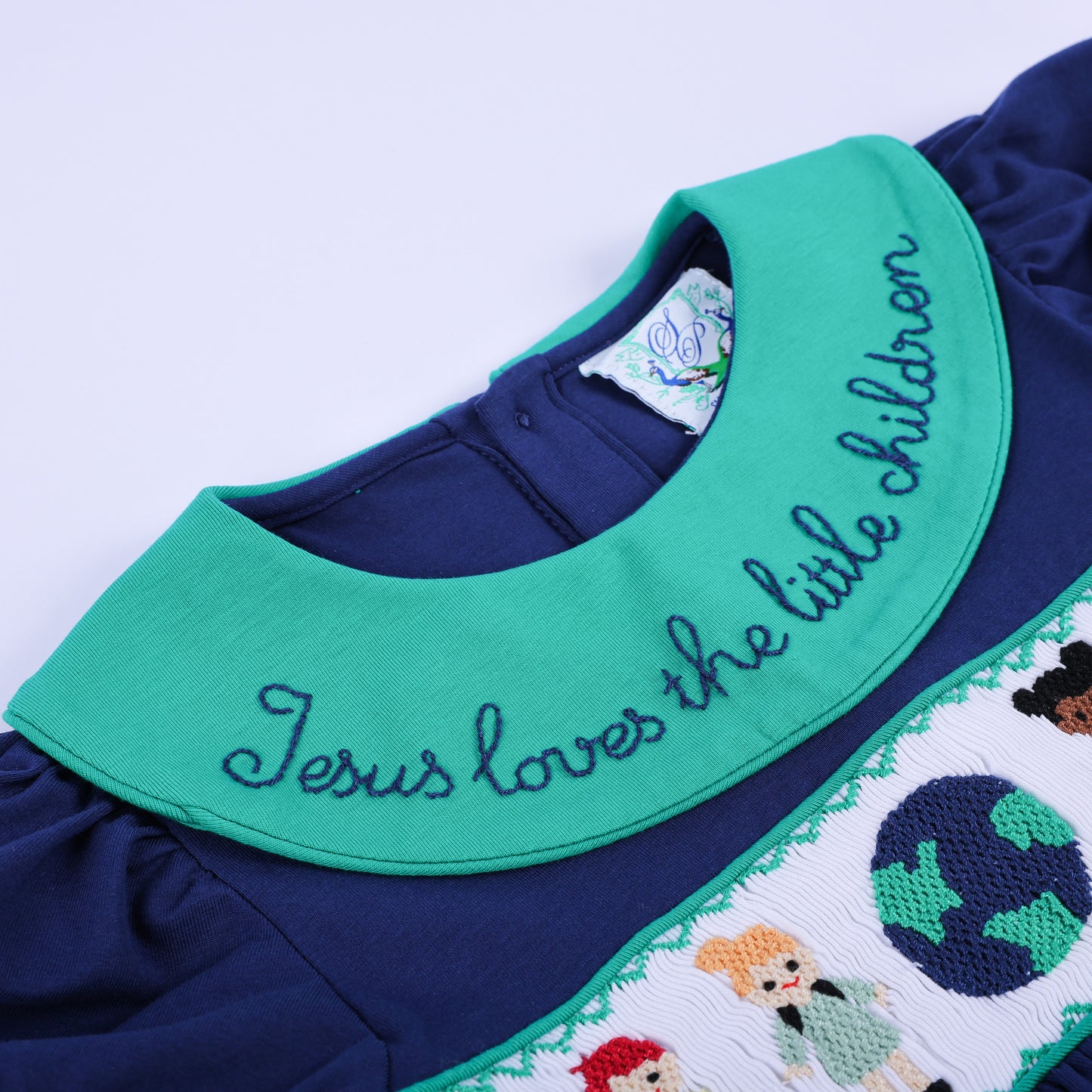 Angled close-up of the navy smocked dress, highlighting the green embroidered collar and detailed hand-smocked bodice.
