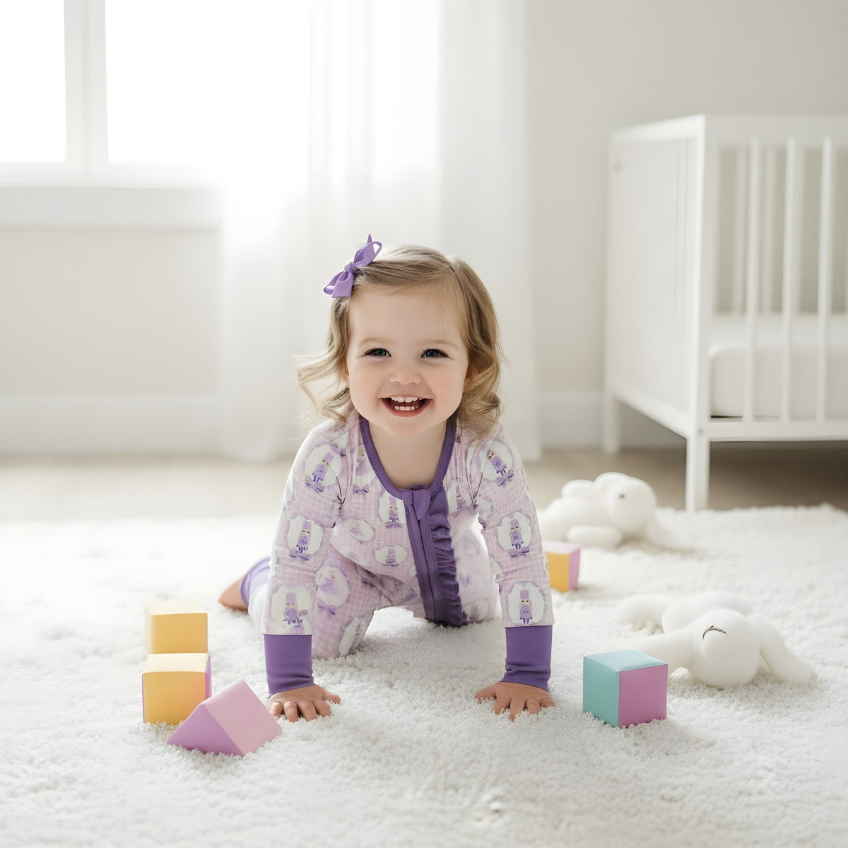 Playful baby girl crawling on a white nursery rug wearing the purple Nutcracker ballet ruffle girls zippy sleeper.