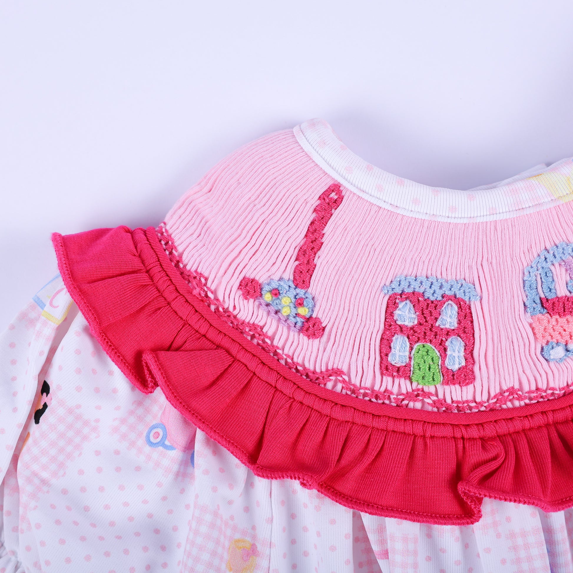 Macro shot of hand-embroidered nostalgic toy phone and pink dollhouse on Dolly & Me smocked clothing bubble.