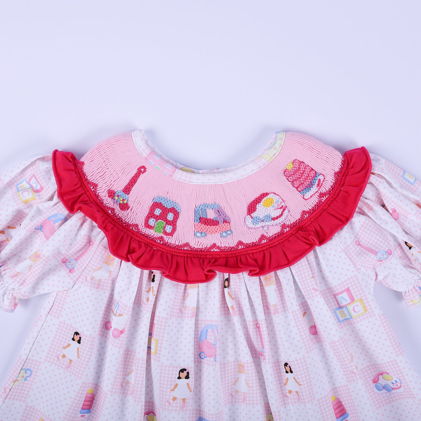 Detailed front view of Dolly & Me hand smocked ruffle collar with embroidered vintage childhood toys on tunic top.