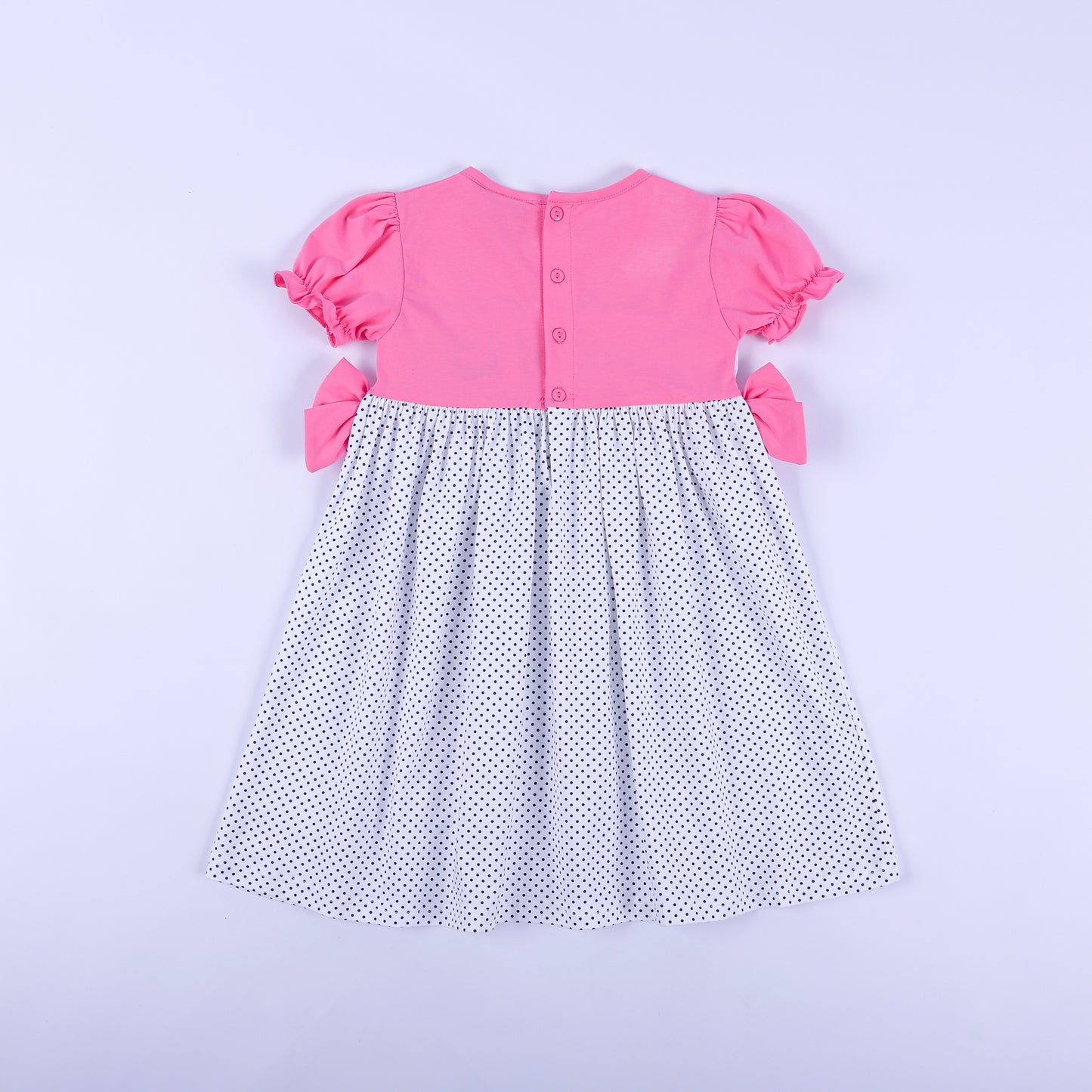 Full back view of girls pink bodice and polka dot skirt dress showing pink button closures and side bows.