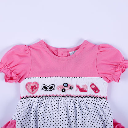 Close-up of hand-smocked bodice with pink embroidered fashion icons including heart, car, high heel, and sunglasses.