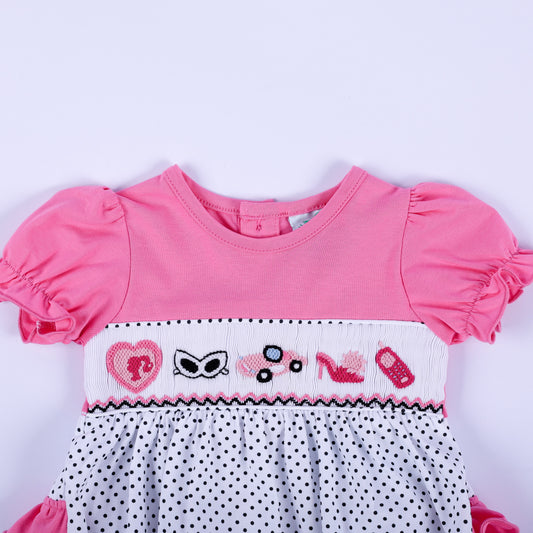 Close-up of hand-smocked bodice with pink embroidered fashion icons including heart, car, high heel, and sunglasses.
