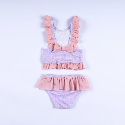 Back view of girls purple gingham two-piece swimsuit with ruffled straps and decorative pink back bow.