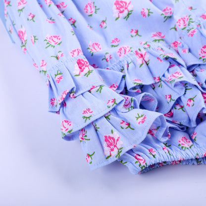 Detailed close-up of layered fabric ruffles on the back seat of light blue floral smocked baby romper.