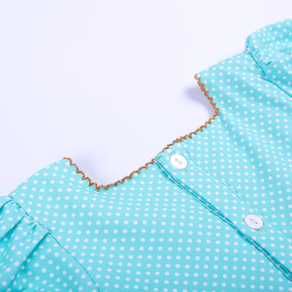Detailed close-up of back button closure on aqua polka dot hand-smocked top with gold picot trim detail.