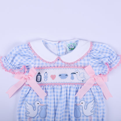 Upper view of the baby gender reveal smocked bubble romper showing the white Peter Pan collar and pink satin bows.