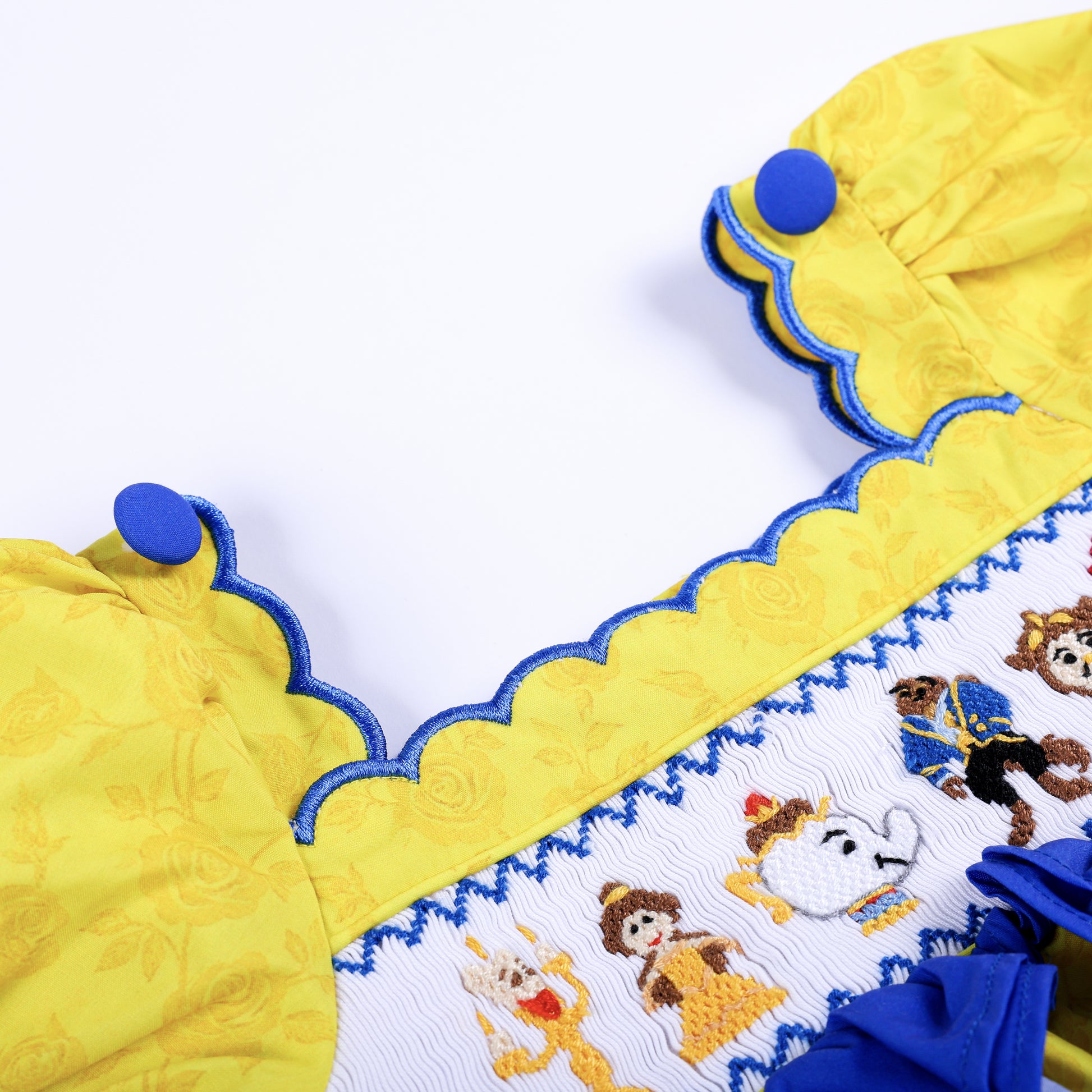 Scalloped blue trim neckline and button detail on girls yellow floral custom hand-smocked fairytale top.