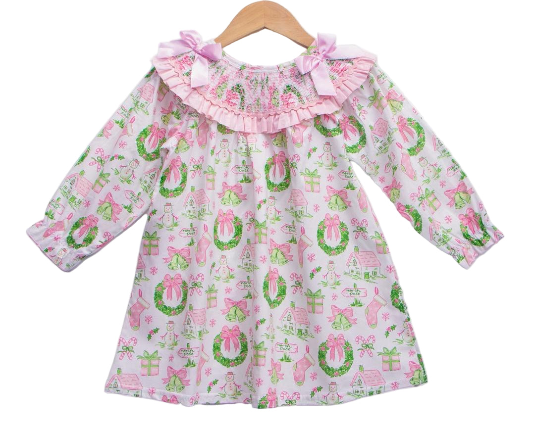 Girls Christmas watercolor smocked dress with pink bows and garland print hanging on a wooden hanger on white back.