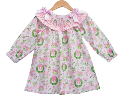 Girls Christmas watercolor smocked dress with pink bows and garland print hanging on a wooden hanger on white back.