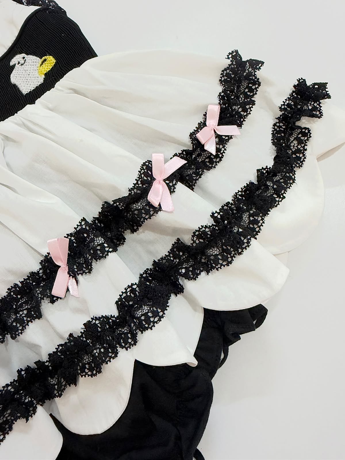 Tiered scalloped ruffles with black lace trim and pink bows on girls Halloween bubble romper