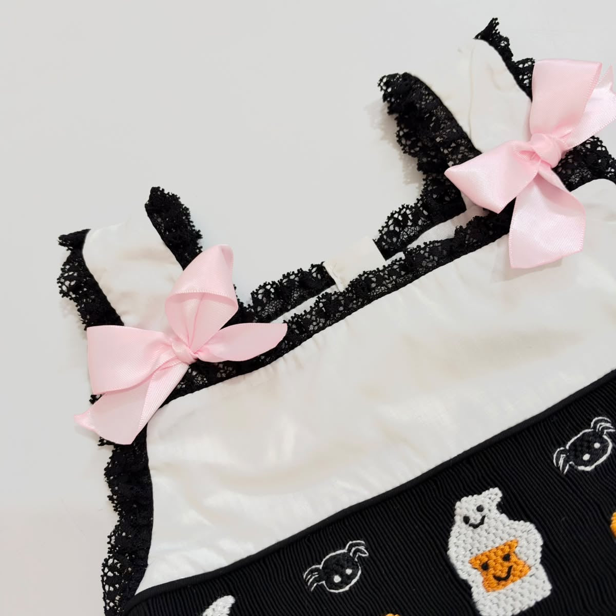 Pink satin shoulder bows and black lace trim on girls hand-smocked Halloween ghost bubble