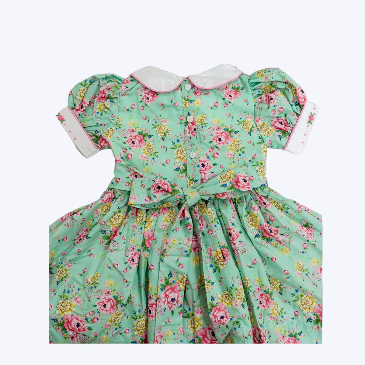 Back of girls mint floral smocked dress featuring button placket and tied sash bow
