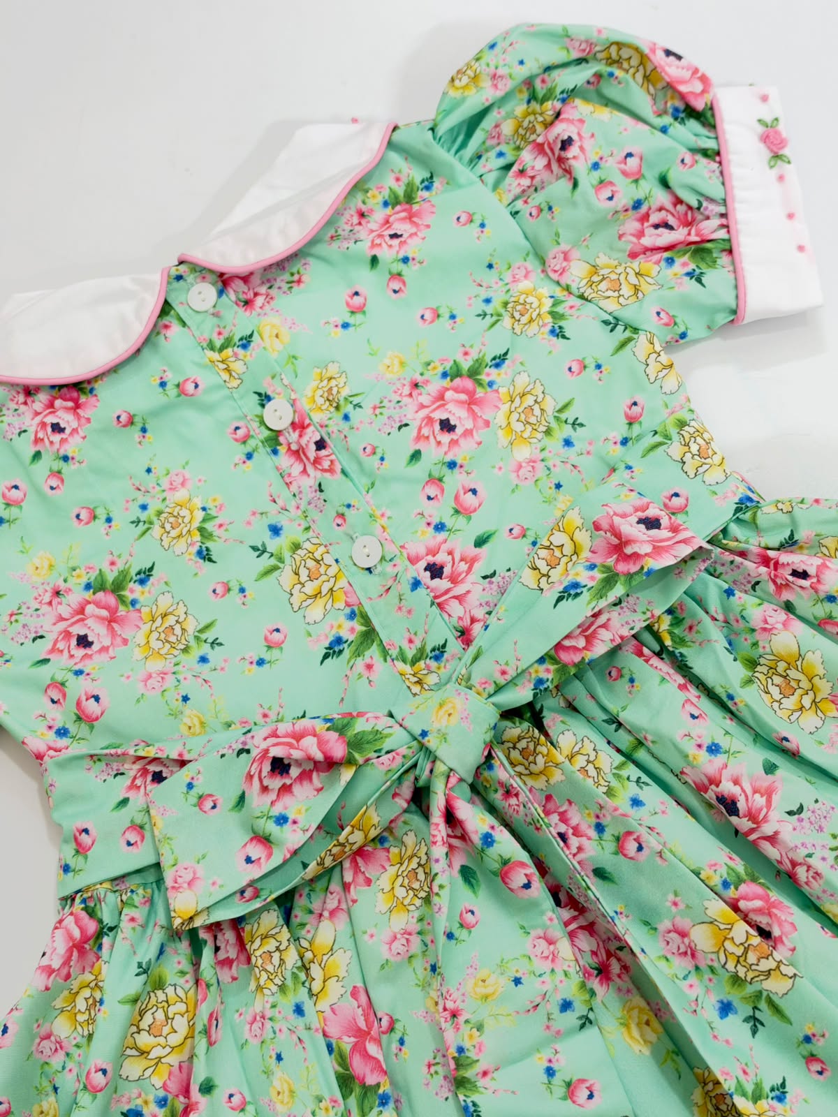 Detail of tied waist sash bow and back button closure on girls mint floral dress