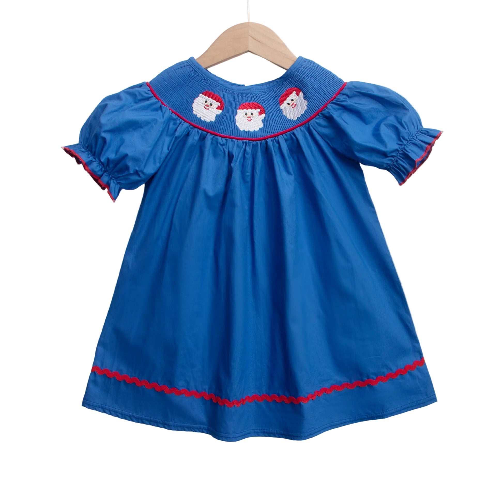 Girls navy blue smocked Christmas dress with three white Santa faces on the bodice, red rickrack trim, and short puff sleeves.