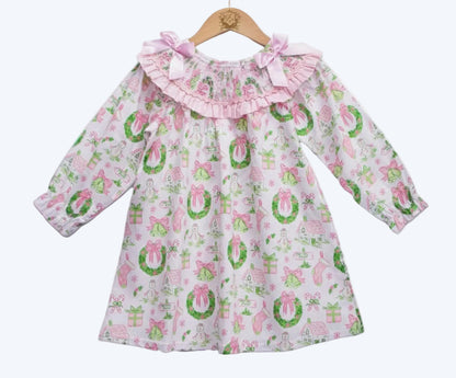 Front view of girls pink watercolor smocked Christmas dress with garland pattern displayed on a wooden hanger.