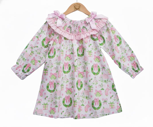 Front view of girls pink watercolor smocked Christmas dress with garland pattern displayed on a wooden hanger.