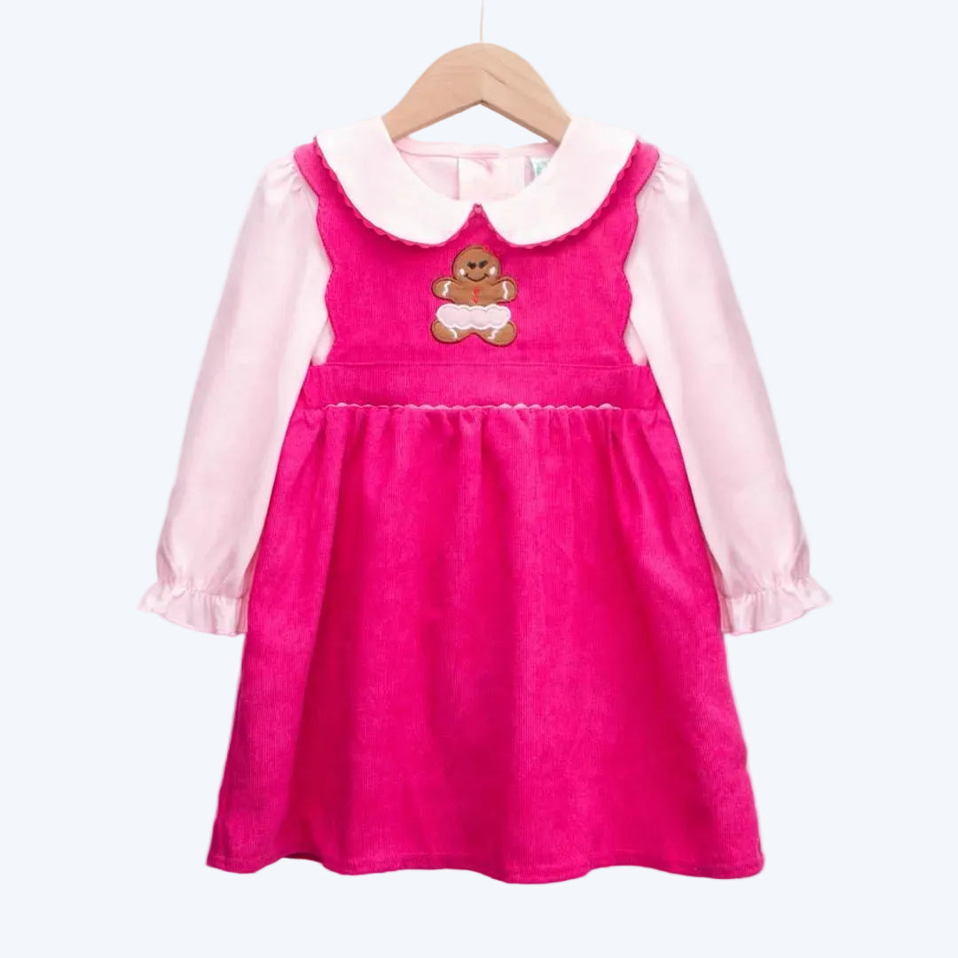Girls pink corduroy dress with cute gingerbread applique and long sleeve Peter Pan collar shirt on white background.