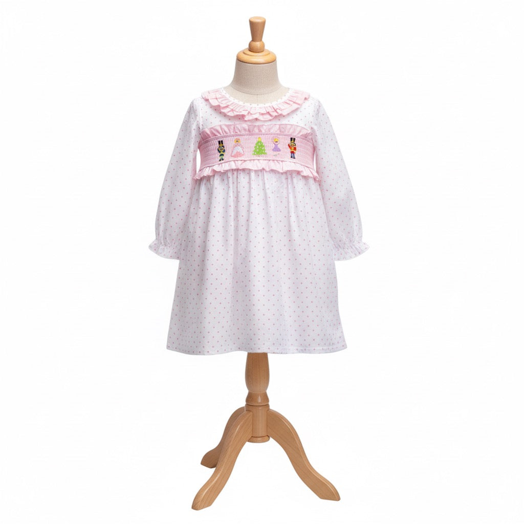 Girls pink Nutcracker smocked dress with polka dot pattern displayed on a wooden mannequin dress form.