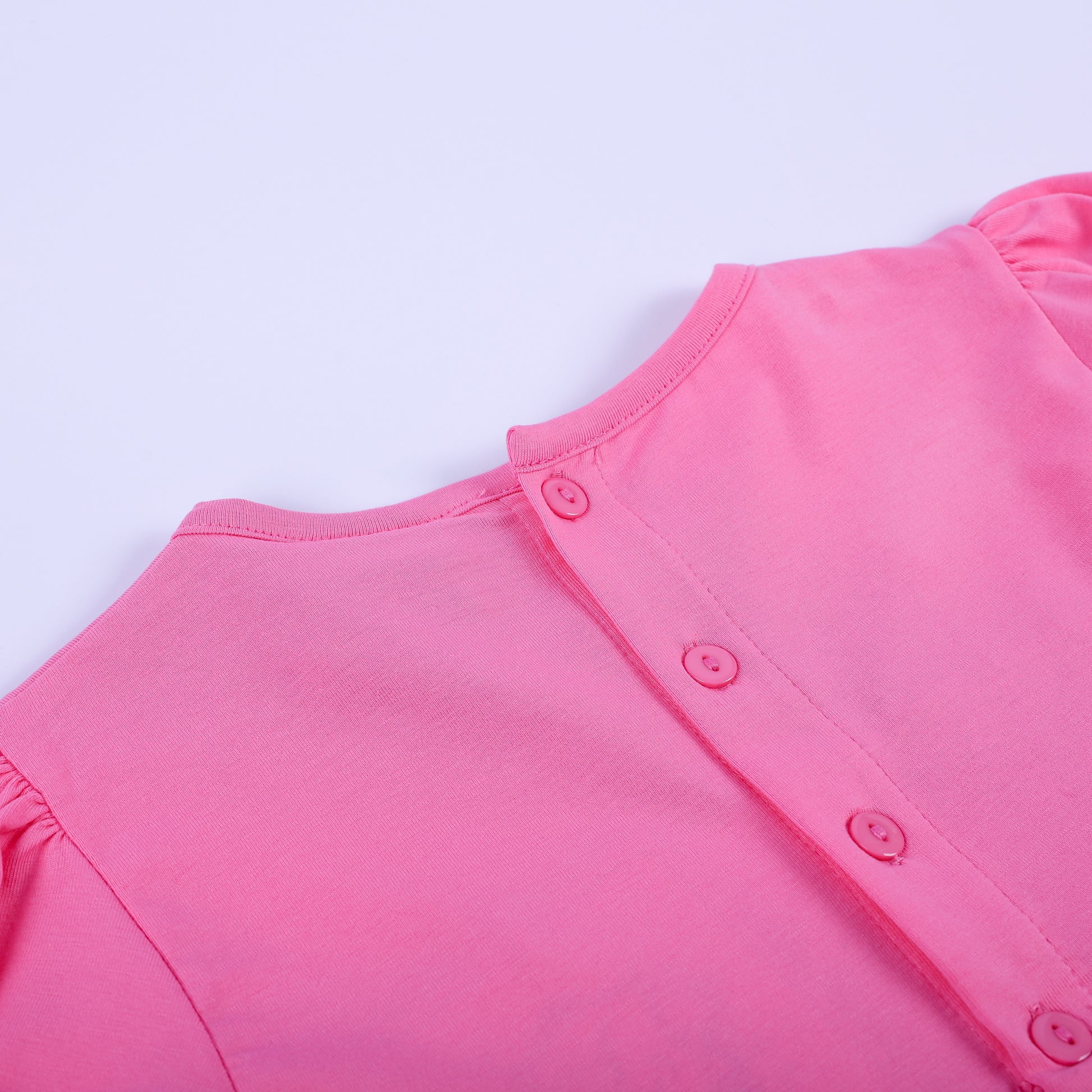 Close-up view of pink button closures on the back bodice of girls fancy hand smocked polka dot dress.