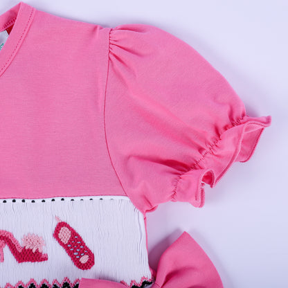 Detail view of ruffled pink puff sleeve and hand embroidered smocking on girls fancy polka dot dress.