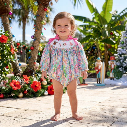 A toddler wears the smocked Christmas bubble romper.