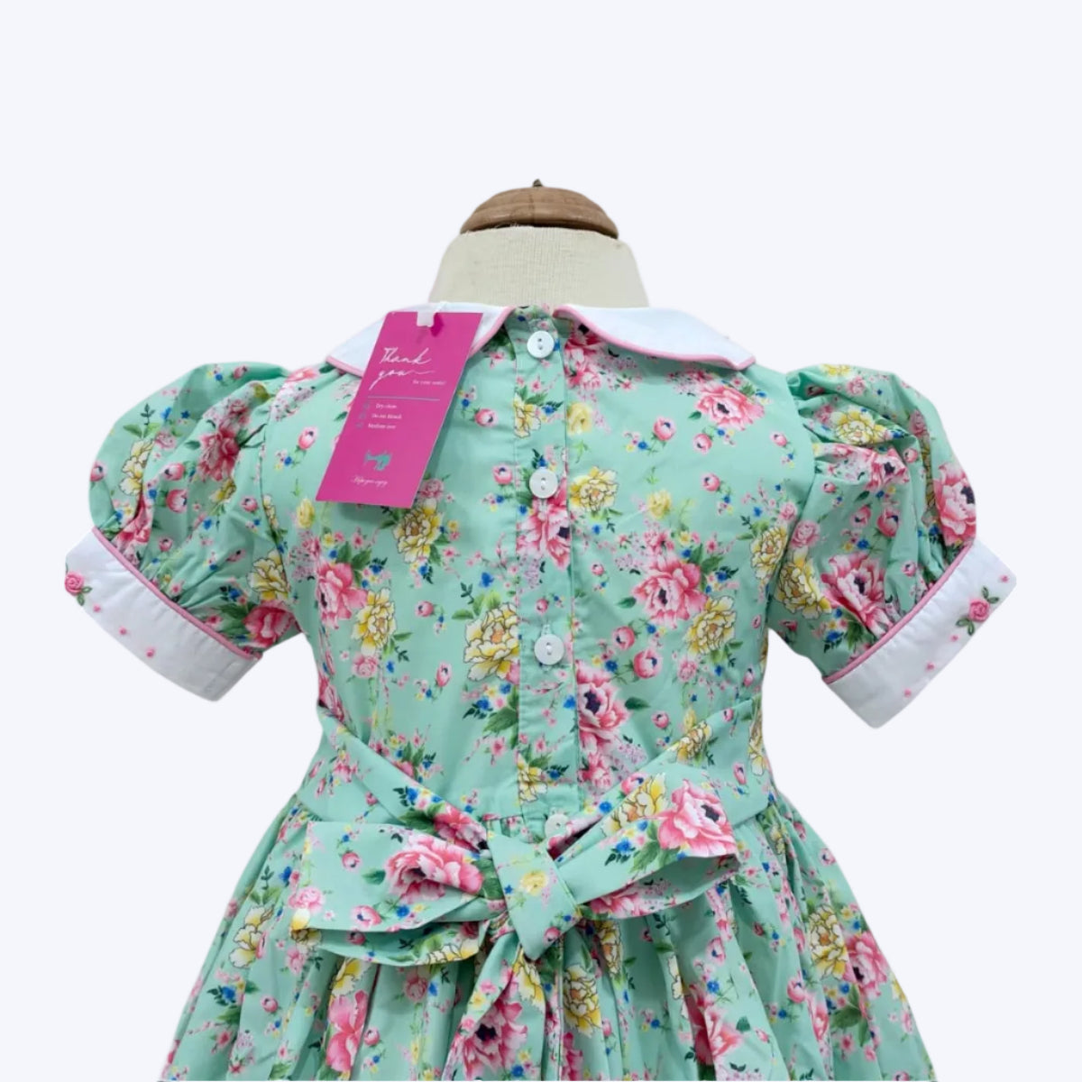 Mannequin back view of girls mint floral dress with Peter Pan collar and sash bow